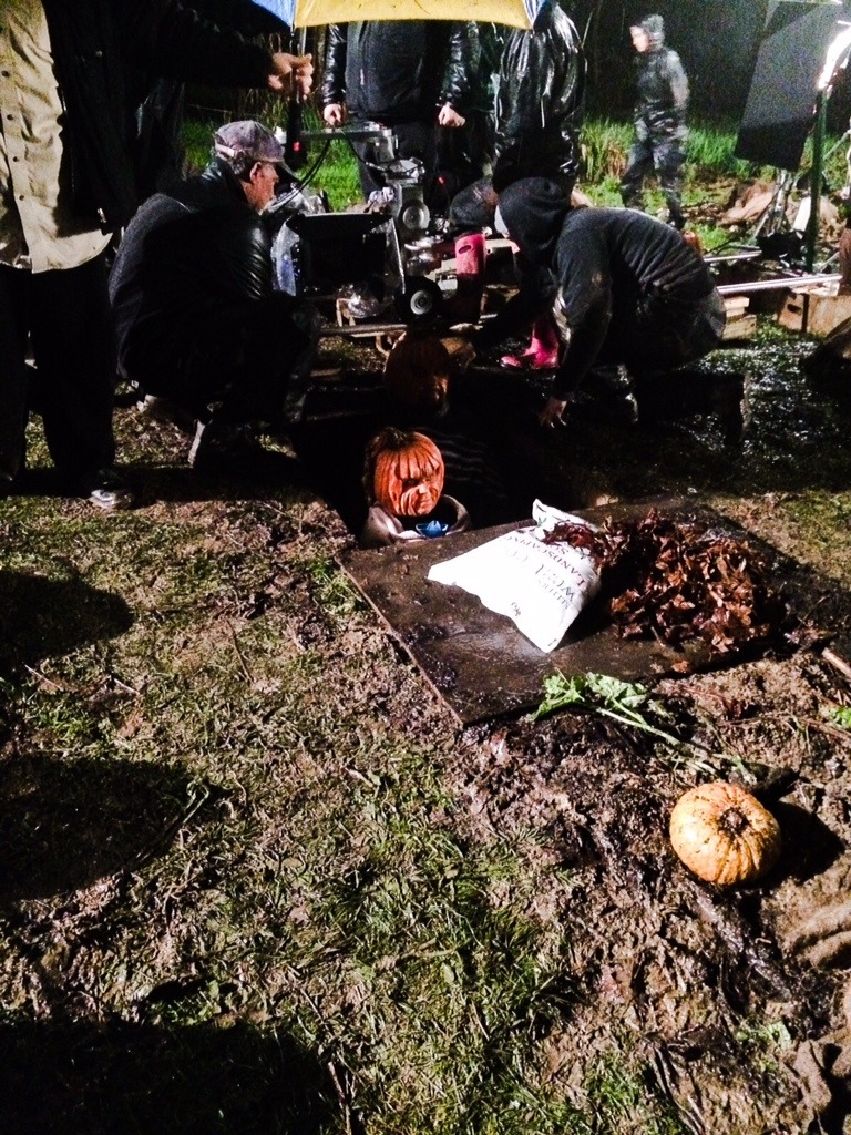 A behind the scenes photo, wearing pumpkin prosthetics Sarah-Jane Redmond is about to be buried up to her neck by the production crew in rather cold and wet conditions on The Haunting Hour - Return of the Pumpkin Heads (Credit: Side Street Post/The Hub).