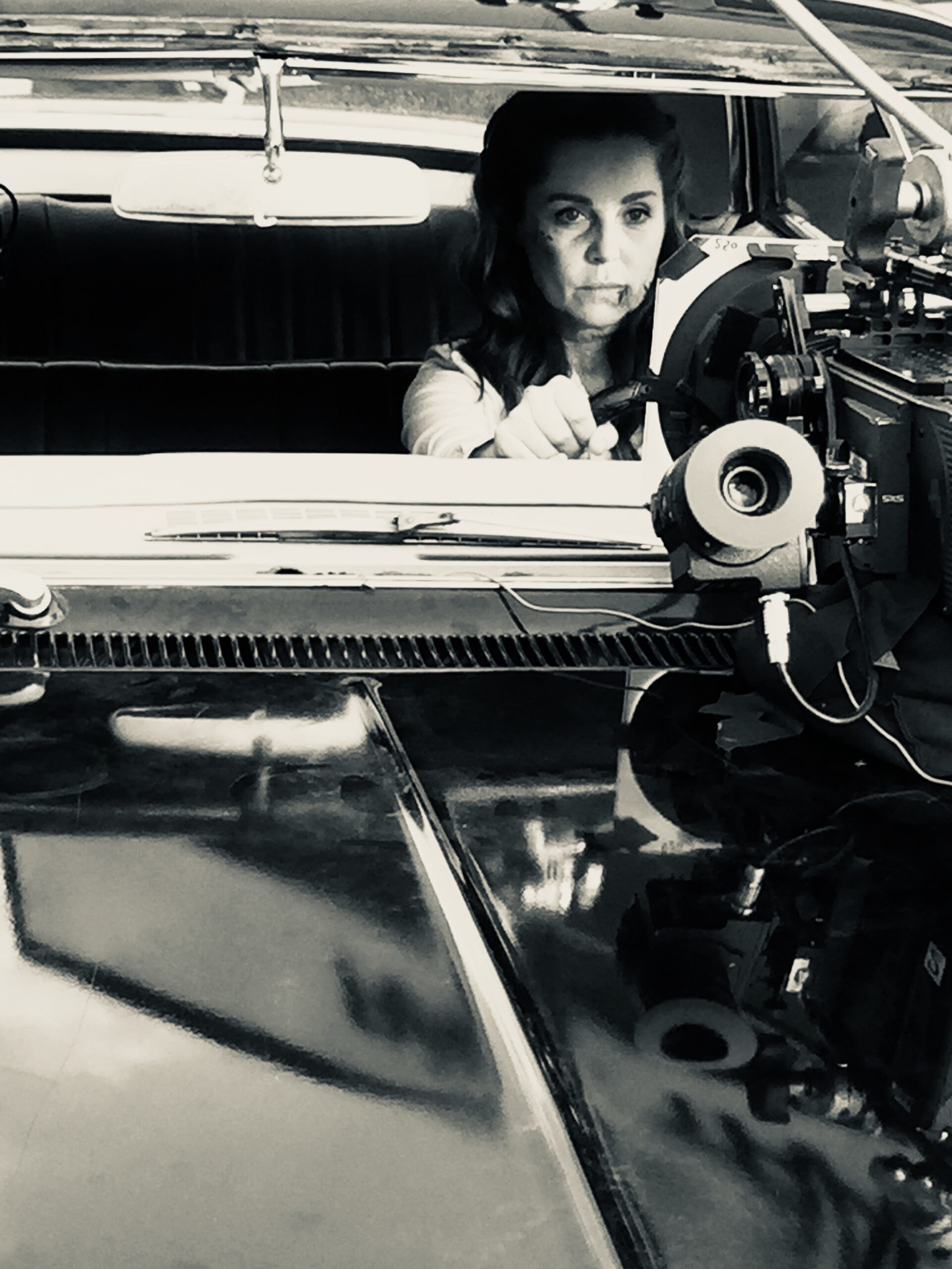 A behind the camera production shot of a beaten up Sarah-Jane Redmond, behind the wheel of 'Baby' on TV series Supernatural.